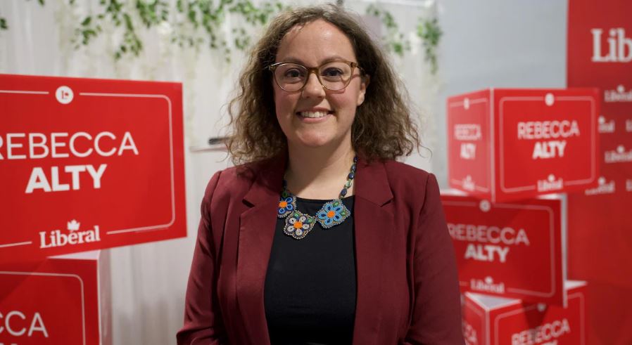 Une femme se tient devant des pancartes à son nom pour le Parti libéral du Canada, à Yellowknife, aux Territoires du Nord-Ouest, le 28 avril 2025.