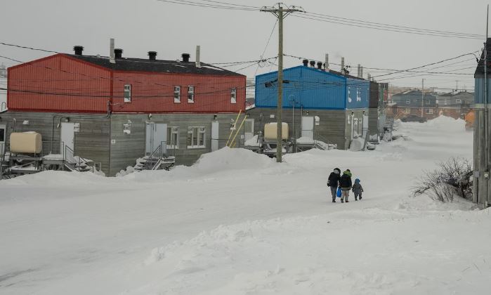 Des gens marchent dans une rue aux maisons colorées.