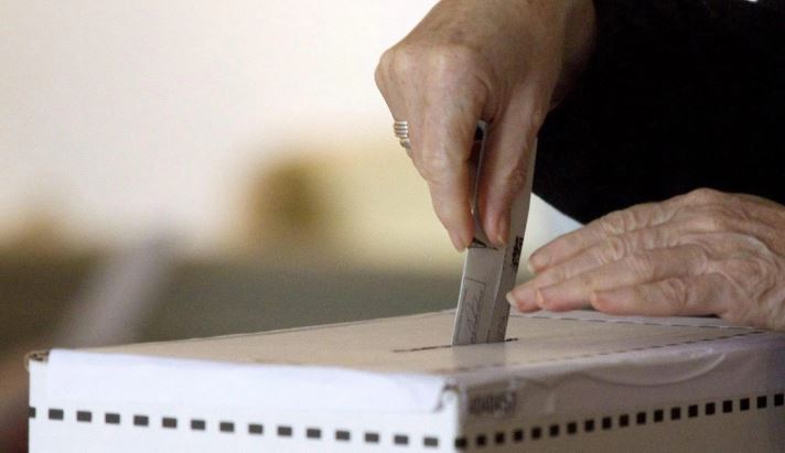 Une femme dépose son bulletin de vote dans une boîte de scrutin.
