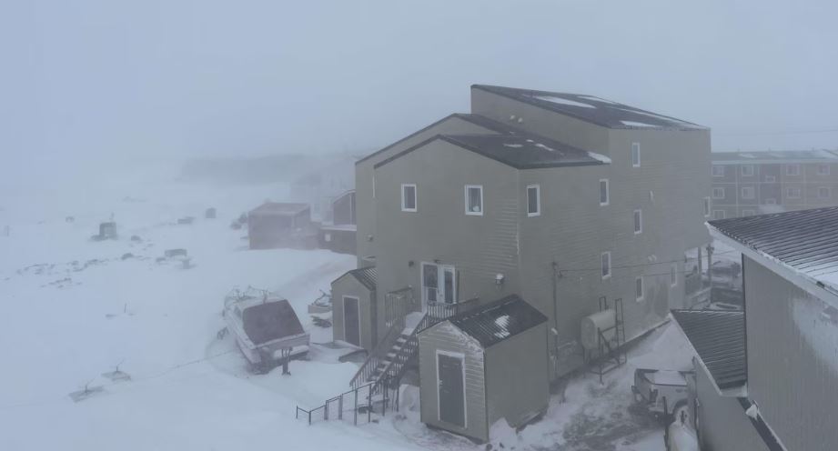 Une vue depuis un balcon de maisons enneigées à Iqaluit durant un blizzard, le 15 mai 2025.