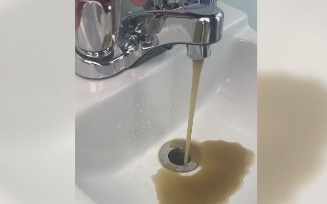 Un robinet crache de l'eau sale.