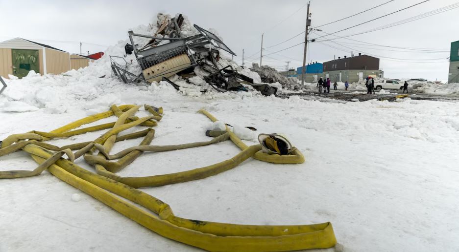 Une lance à eau devant un amas de ferraille et de neige.