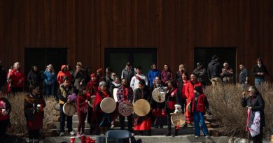 Des personnes habillées de rouge tiennent des tambours derrière le centre culturel Kwanlin Dün, le 5 mai 2025.