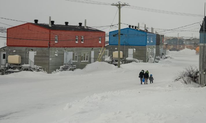Des gens marchent dans une rue aux maisons colorées.
