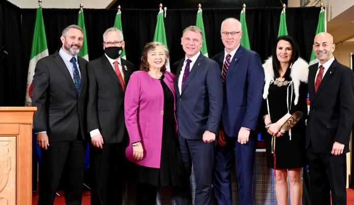Le premier ministre Ranj Pillai et les membres de son nouveau cabinet sont debout devant plusieurs drapeaux.
