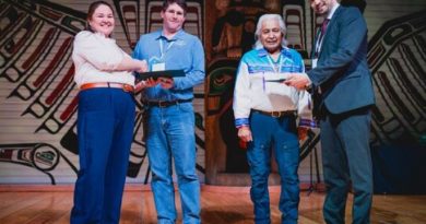 Quatre personnes recoivent des prix et regardent la caméra en souriant.