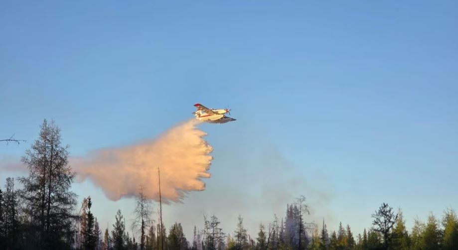 Un avion-citerne déverse de l'eau sur un incendie de forêt près de Fort Smith, dans les Territoires du Nord-Ouest, le 1er juin 2025.