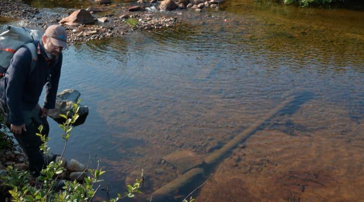 Un homme debout près d'un cours d'eau.