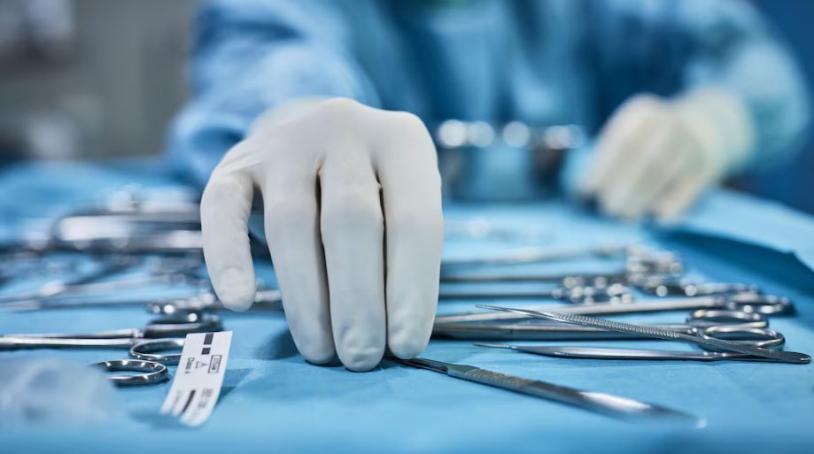 Les main d'un soignant manipulent des instruments chirurgicaux.