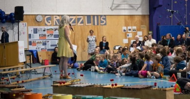 Une personne debout devant un public d'enfants et d'adultes dans le gymnase de l'École Emilie Tremblay, à Whitehorse, au Yukon.
