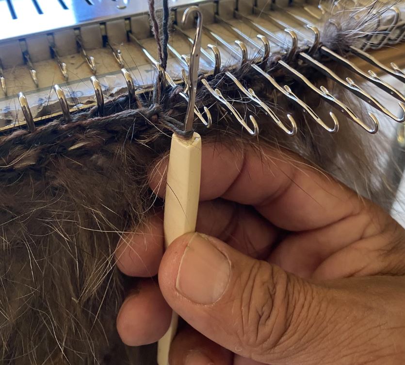 Un gros plan de la main de D’Arcy Moses, qui tient un crochet à tricoter.