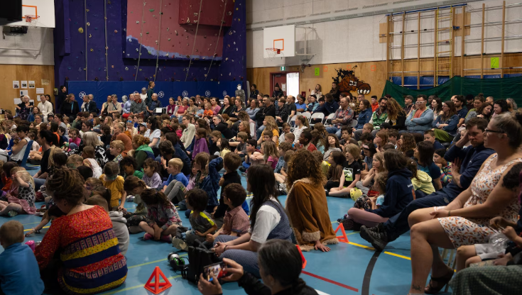 Beaucoup de monde assis par terre ou sur des chaises dans le gymnase de l'École Émilie-Tremblay, à Whitehorse.