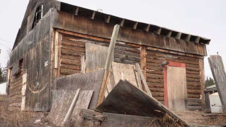 Une maison en bois avec des plaque de bois entreposées autour.