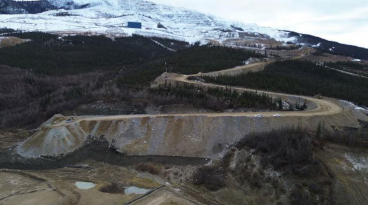 Plan d'ensemble d'un talus de terre sur lequel circulent des camionnettes à l'automne.