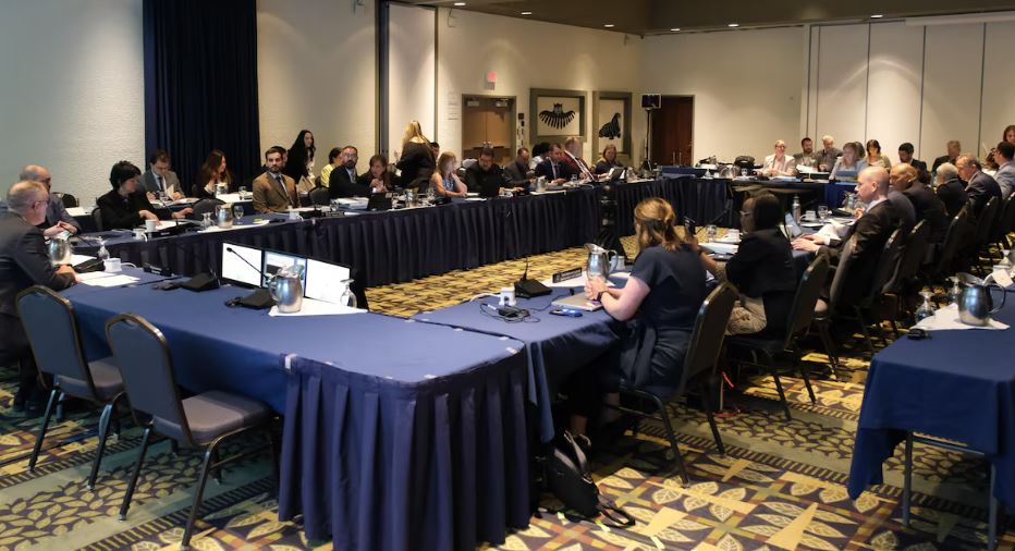 Des gens assis autour de tables dans une salle de conférence, le 27 juin 2025.
