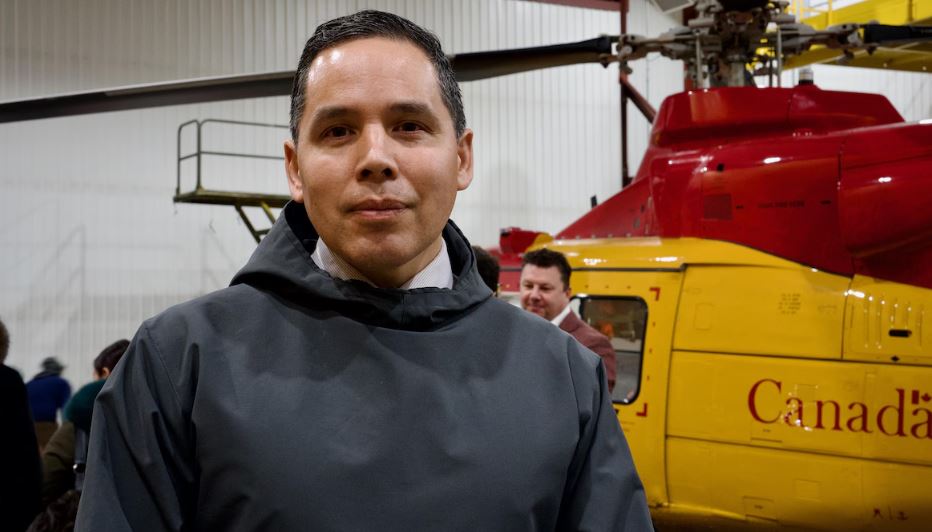 Le président de l'organisme national Inuit Tapiriit Kanatami, Natan Obed, se tient devant un hélicoptère dans un hangar des forces armées canadiennes à Iqaluit, au Nunavut, le 18 mars 2025.