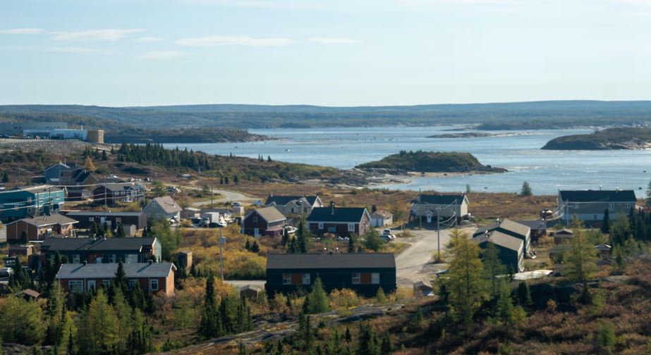Le village de Kuujjuak au bord de l'eau, entouré de forêt.