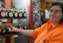 Une femme travaille à l'ordinateur de la caisse d'un magasin de siouvenirs. Elle porte une veste orange.