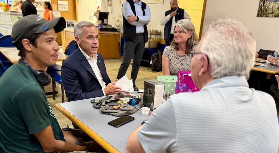 Mark Carney s'assoit à une table avec des citoyens dans une pizzeria.