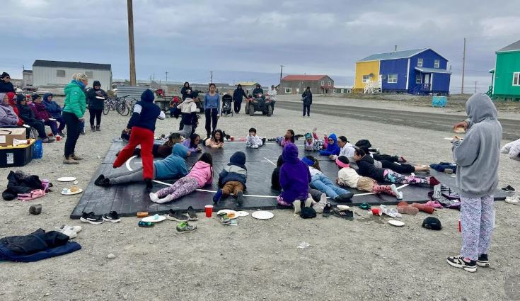 Deux jeunes allongés face contre terre sur un matelas de lutte, dehors.