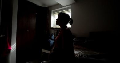 Une femme assise dans une chambre sombre.