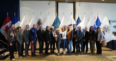 Une quinzaine de personnes posent devant des drapeaux à Yellowknife, le 21 juillet 2025.