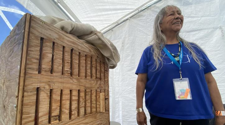 Joanne Williams se tient debout près d'une boîte en bois cintré.