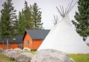 Un tipi entouré de chalets près d'un cours d'eau.