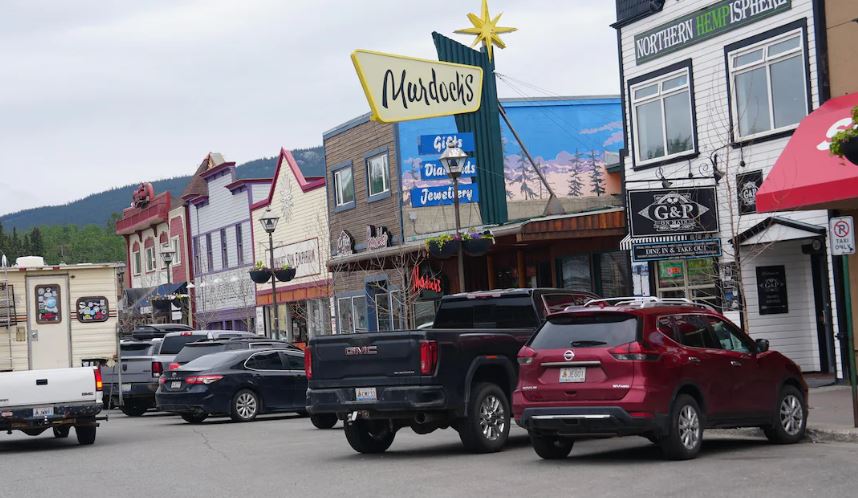 Des voitures sont stationnées devant des devantures de magasins colorées du centre-ville de Whitehorse.