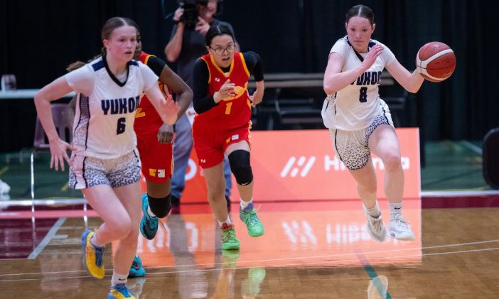 Quatre jeunes femmes jouent au basketball.