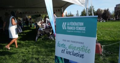 Un panneau de la Fédération franco-ténoise devant une tente abritant des exposants.