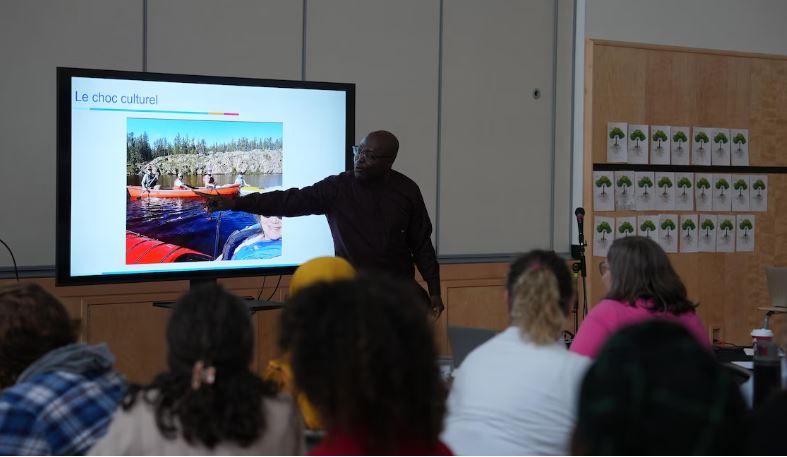 Hemedzo Mensah montre une diapositive intitulée « le choc culturel » à son public dans le gymnase de l'école Allain St-Cyr.