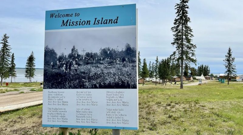 Un panneau à l'avant-plan d'un camp sur le site de Mission Island.