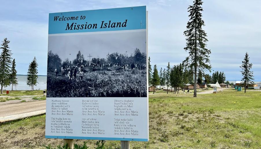 Un panneau à l'avant-plan d'un camp sur le site de Mission Island. 