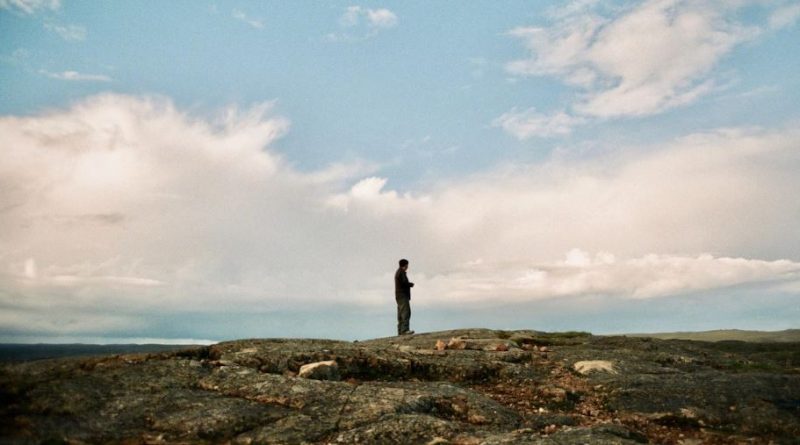Un homme regarde vers l'horizon, dans la toundra.
