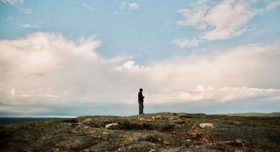 Un homme regarde vers l'horizon, dans la toundra.