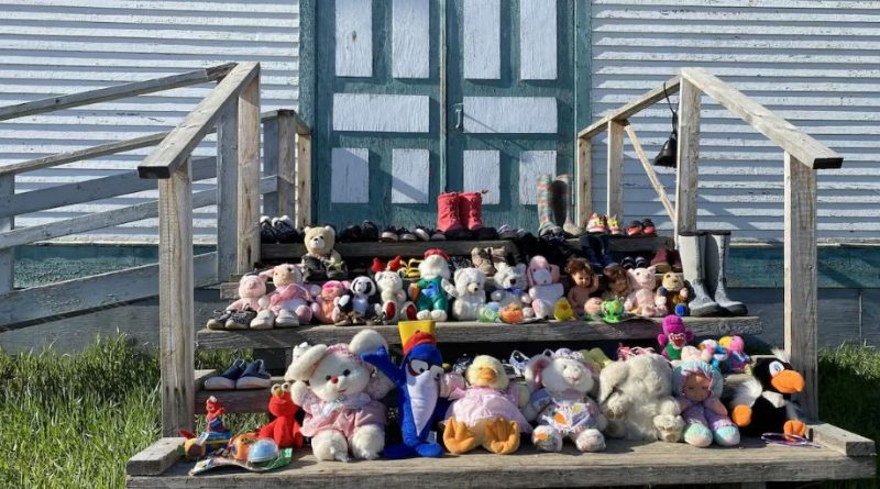 Des peluches, jouets et petites chaussures remplissent les trois marches devant l'entrée de l'Église catholique à Fort Resolution, aux T.N.-O.