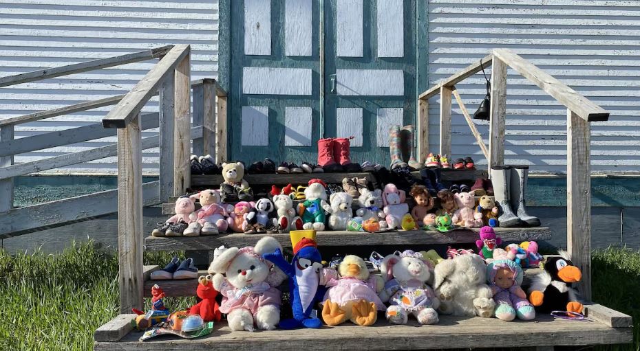Des peluches, jouets et petites chaussures remplissent les trois marches devant l'entrée de l'Église catholique à Fort Resolution, aux T.N.-O.