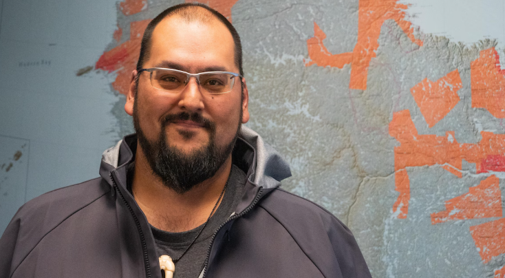 Portrait d'Adamie devant une carte du territoire.