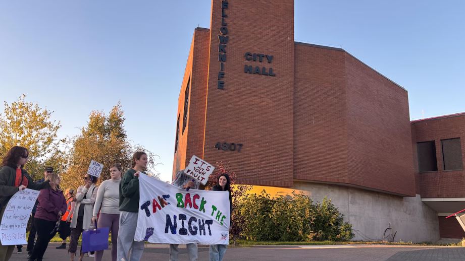Des personnes avec une bannière Take Back the Night devant l'hôtel de ville de Yellowknife, le 18 septembre 2025.
