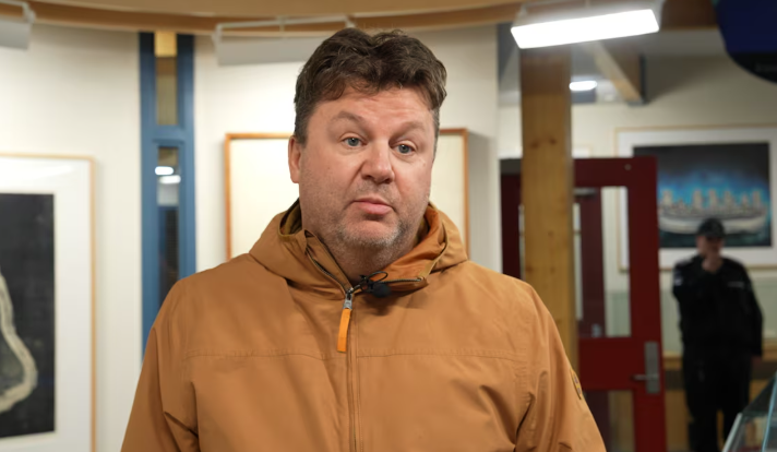 Un homme parle devant une caméra.