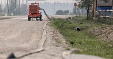 Un tuyau de gicleurs est inslallé le long d'une rue.