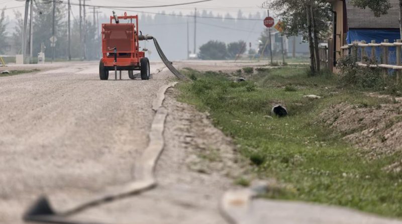 Un tuyau de gicleurs est inslallé le long d'une rue.