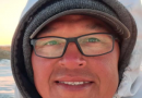 Un homme regarde la caméra en souriant.