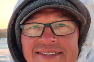 Un homme regarde la caméra en souriant.