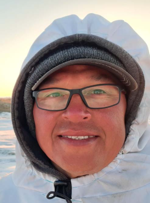 Un homme regarde la caméra en souriant.