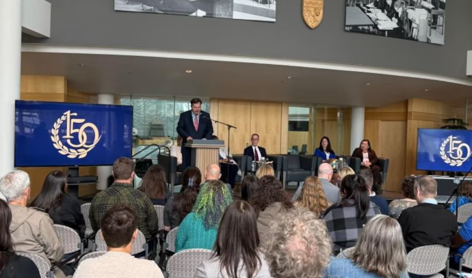Des juges de la Cour suprême du Canada devant un public avec des logos du 150e anniversaire du plus haut tribunal du pays.