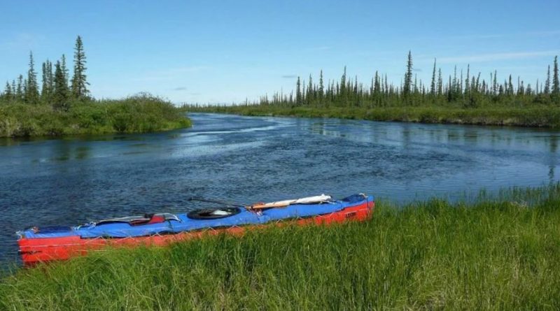 Un canot est accosté sur l'herbe au bord d'une rivière.