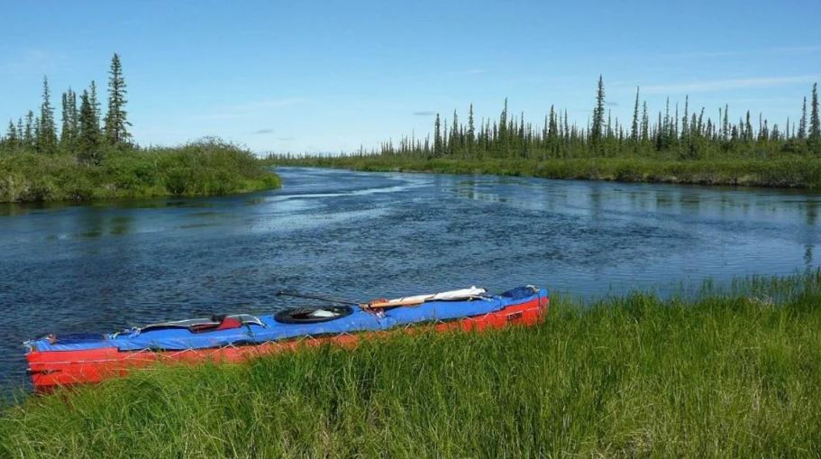 Un canot est accosté sur l'herbe au bord d'une rivière.