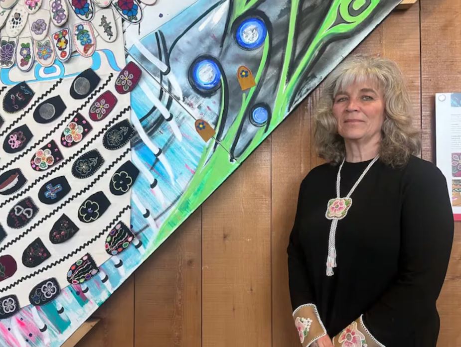 Une femme debout et fixant du regard l'objectif d'une caméra.